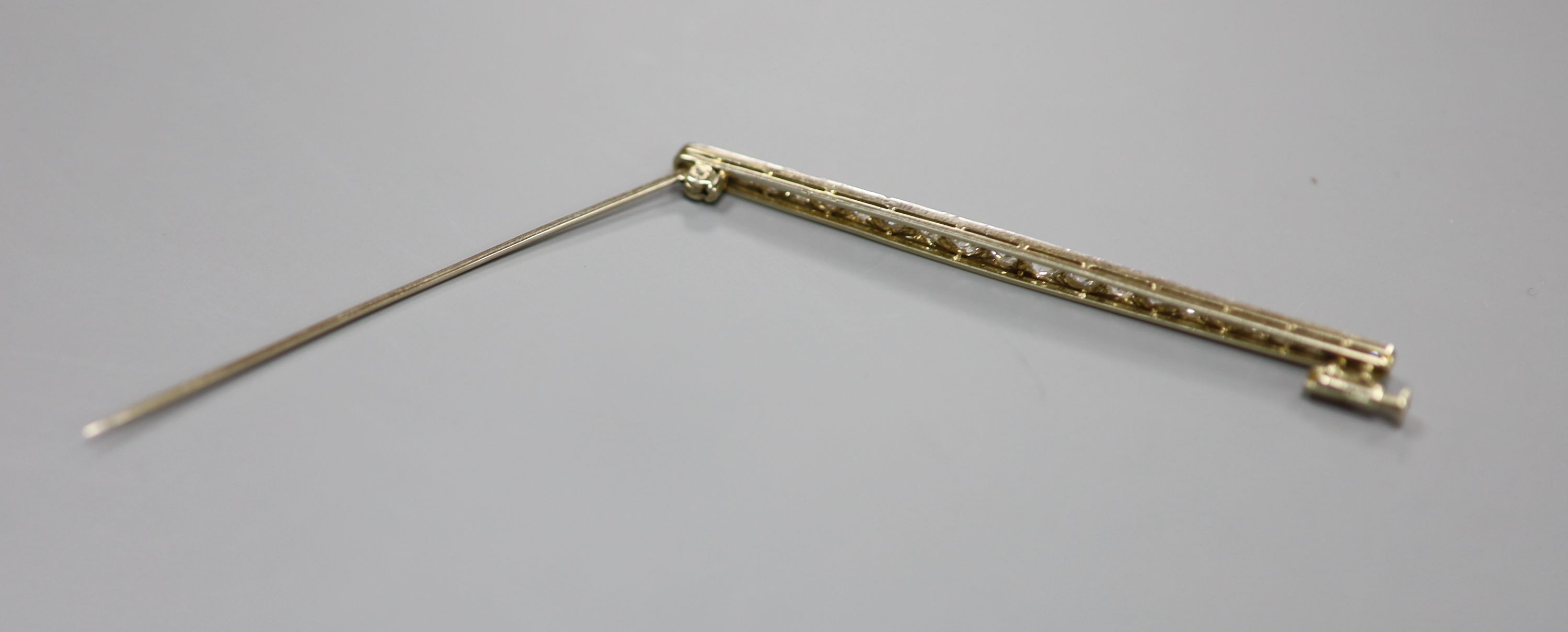 An early 20th century yellow metal and graduated twenty stone diamond set bar brooch, 67mm, 4.9 grams.